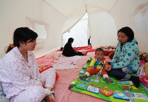 Resident Chen Dashuang (R) plays with her son in a tent at a temporary shelter site in Lushan County of Ya'an City, southwest China's Sichuan Province, April 21, 2013. Several temporary shelter sites can be seen in Lushan County and the life supplies in these shelter sites are sufficient. A 7.0-magnitude earthquake jolted Lushan County on April 20 morning. (Xinhua/Li Jian)