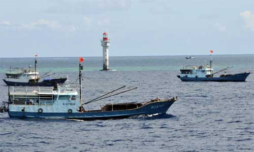 Fishing vessels sail past a beacon of Zhubi Reef of south China Sea on July 18, 2012. A fleet of fishing vessels from China's southernmost province of Hainan departed from Yongshu Reef on Tuesday night. The fleet arrived at Zhubi Reef at about 10 a.m. Wednesday. The fleet of 30 boats, the largest ever launched from the island province, planned to fish and detect fishery resources near Zhubi Reef. Photo: Xinhua