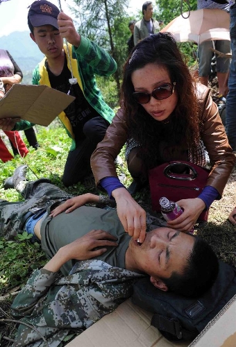 A woman gives medical treatment to a soldier saved from a rescue car from Chengdu Military Region which falls off a cliff into a river in southwest China's Sichuan Province, April 20, 2013. Two of the 17 soldiers in the car have died by 11:30 p.m. Saturday Beijing Time. A total of 156 people have been killed in the 7.0-magnitude earthquake in Sichuan's Lushan as of 8:50 p.m. Saturday, according to the China Earthquake Administration. (Xinhua) 