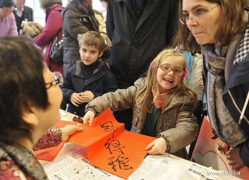 A girl smiles with a calligraphy work of her Chinese name during an event to celebrate the Spring Festival at the 4th Brussels European School in Brussels, capital of Belgium, on Feb. 2, 2013. The Chinese embassy in EU and the 4th Brussels European School held an event to introduce Chinese Spring Festival to hundreds of pupils and their parents Saturday.(Xinhua/Ye Pingfan) 