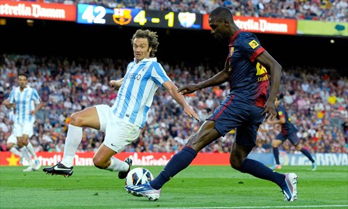 Eric Abidal (right) of Barcelona tries to control the ball against Diego Lugano of Malaga on Saturday. Photo: CFP