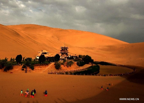 Tourists visit the scenic spot of the Mingsha Mountain and Crescent Spring in Dunhuang City, northwest China's Gansu Province, May 21, 2013. Dunhuang has received about 749,200 tourists in the first four months of 2013, increasing 58.63 percent year on year. (Xinhua/Nie Jianjiang)&nbsp; 