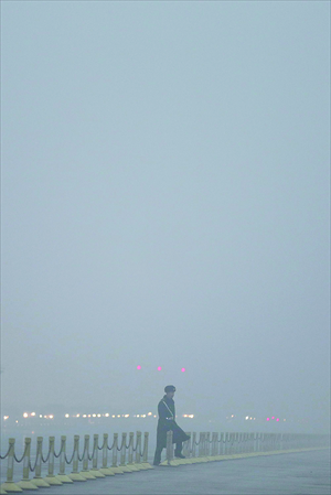 A Chinese armed police officer passes through Chang'an Avenue during the flag-raising ceremony in Tiananmen Square, as severe pollution hit Beijing on Tuesday. Photo: CFP