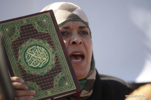 A Palestinian woman holds up the Koran, Islam's holy book, during a demonstration against the Israeli policeman who kick the Koran outside Damascus gate, in the old city of Jerusalem, on March 6, 2013. (Xinhua/Awad) 