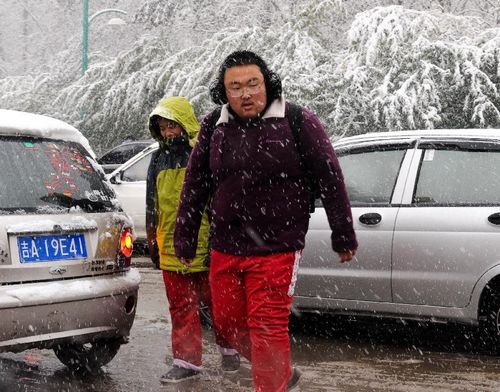 Citizens walks on a snow-covered street in Changchun, capital of Northeast China's Jilin Province, October 22, 2012. Most parts of Jilin witnessed snowfall on Monday. Photo: Xinhua