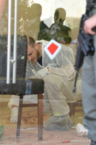  An Israeli security officer inspects the scene of the bank robbery in Beersheva, southern Israel, on May 20, 2013. At least four people were killed in an armed bank robbery that took place on Monday in south Israeli city of Beersheva, Israel channel 2 citing the Magen David Adom emergency services as reporting. During the standoff with police, one of the robbers committed suicide. (Xinhua/Yin Dongxun) 