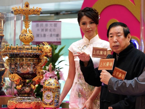 Artist Zhang Tonglu (R), introduces a cloisonne work he made during an exhibition in south China's Hong Kong, Jan. 22, 2013. An exhibition of Zhang Tonglu's cloisonne art works was held here on Tuesday, showing 22 pieces of cloisonne works. (Xinhua/Li Peng) 