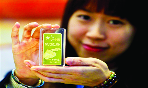 A woman in Foshan, South China’s Guangdong Province holds a gold bar bearing an image of the Diaoyu Islands Thursday. Gold and silver bars with this theme are popular recently, as many consumers hope to show patriotism by purchasing products related to the islands, the subject of a dispute between China and Japan. The current gold price is around 330 yuan ($53) per gram, and the 100-gram gold bar is sold at roughly 35,000 yuan. Photo: CFP