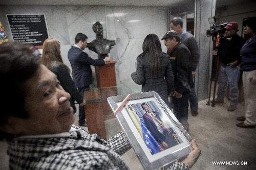 A woman holds a portrait of Venezuelan President Hugo Chavez after the news of his death was released, in Mexico City, capital of Mexico, on March 5, 2013. Venezuelan President Hugo Chavez died on March 5. (Xinhua/Pedro Mera)