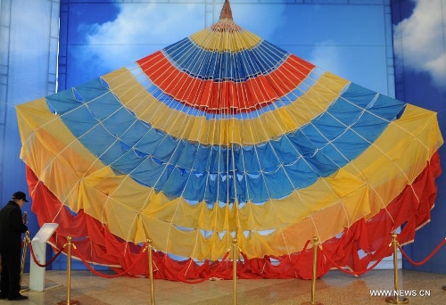 A visitor looks at a parachute presented during the China's Space Exhibition in Hebei Museum in Shijiazhuang, capital of north China's Hebei Province, April 1, 2013. The exhibition which will last till April 7 included the display of space carriers, rocket-launcher models of the Long March series, paintings and photos related to aerospace. (Xinhua/Wang Xiao)&nbsp; 