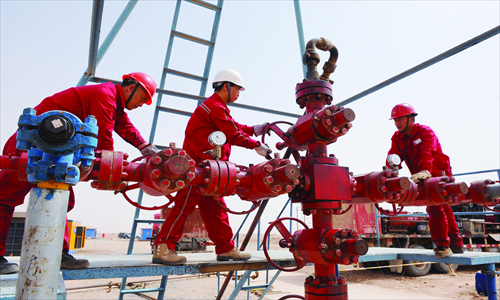 Workers adjust a crude oil production facility at a well in Northwest China's Xinjiang Uyghur Autonomous Region on Sunday. Sinopec's Northwest China branch recently developed a new artificial lift technique to increase pressure in the well in order to lift more heavy oil to the surface. The technique helps increase crude oil output by over 40 tons a day. Photo: CFP