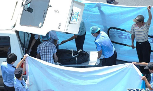 A victim's body is carried away from the scene of a decorated archway toppling accident in Hefang Street, a busy commercial area and tourism destination in Hangzhou, capital of east China's Zhejiang Province, Aug. 12, 2012. Two people were killed and several others injured after a decorated archway, or pailou, suddenly toppled down Sunday morning in Hangzhou. Photo: Xinhua