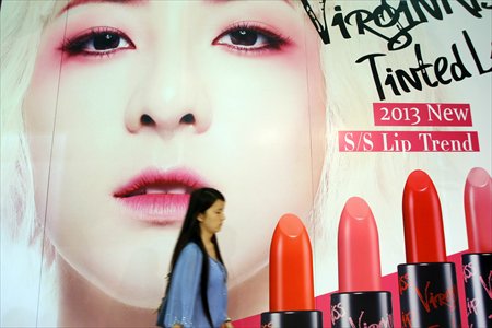 A young woman walks past a cosmetics advertisement billboard at the annual China Beauty Expo in Shanghai on Monday. The expo ran from Monday through Wednesday and mirrors Chinese consumers' rising demand for cosmetics products. Sales revenue in China's cosmetics market rose by 17 percent year-on-year to 134 billion yuan ($21.83 billion) in 2012, according to data from the National Bureau of Statistics. Photo: IC
