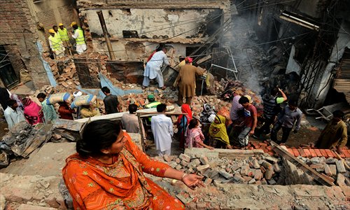 Pakistani Christians search for salvageable belongings from the remains of their razed houses in Lahore on Monday. Pakistani Christians closed missionary schools on Monday in protest after a Muslim mob torched more than 100 Christian homes following allegations of blasphemy. Photo: AFP