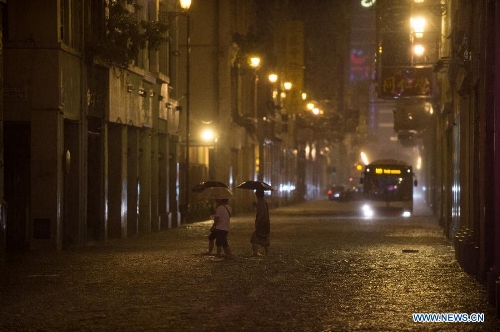Pedestrians walk in rain on a waterlogged road in Macao, south China, May 22, 2013. (Xinhua/Cheong Kam Ka)