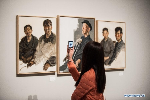 A visitor takes photo of paintings by Chen Danqing during the 
