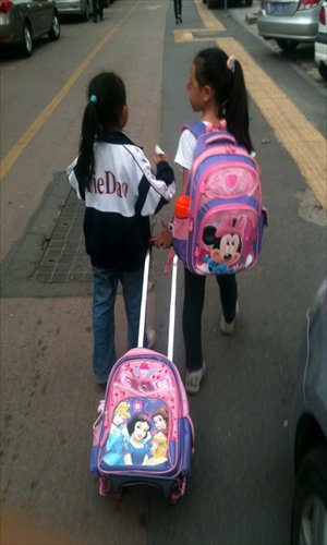 A primary school student pulls a bag behind her as she walks with her classmate after school on a road in Changsha, Hunan Province, on September 25, 2012. Photo: CFP