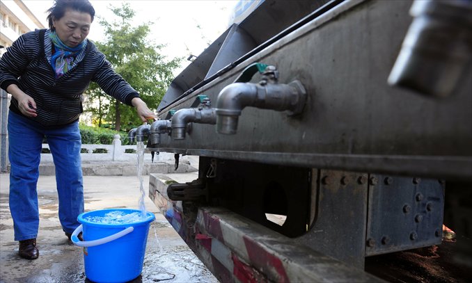 A woman fetches water from an emergency water supply truck in Xinhuili, Chaoyang district, Beijing, following a water cut due to an aging pipe having burst on October 22, 2012. Photo: CFP