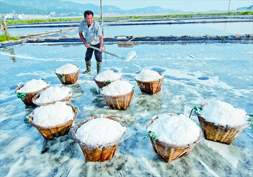 A worker shovels sea salt into bamboo baskets. Photo: CFP