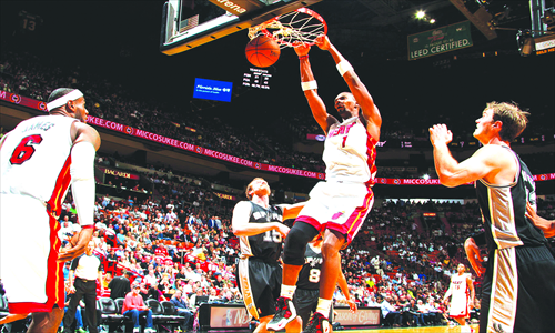 Chris Bosh (in white) of the Miami Heat dunks against the San Antonio Spurs on Friday at AmericanAirlines Arena in Miami, Florida. Photo: CFP