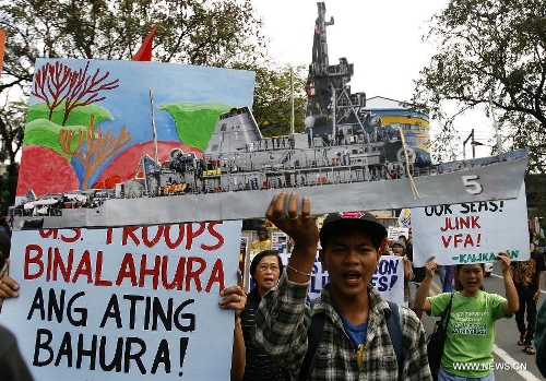 Activists shout slogans as one of them holds a picture of the USS Guardian during a rally near the U.S. Embassy in Manila, the Philippines, Jan. 21, 2013. The protesters called for the pullout of U.S. troops in the Philippines after the U.S. Navy minesweeper USS Guardian (MCM 5) ran aground on Tubbataha Reef. (Xinhua/Rouelle Umali)&nbsp; 
