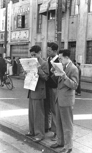 Shanghai men in Western suits reading newspapers on Nanjing Road.