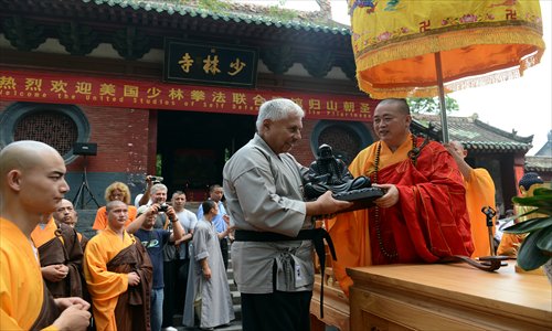 The abbot of Shaolin Temple, Shi Yongxin (right), gives a statue of Buddha to a foreign student during a graduation ceremony at the Shaolin Temple at Mount Songshan in Dengfeng, Central China's Henan Province, on July 3. Photo: IC