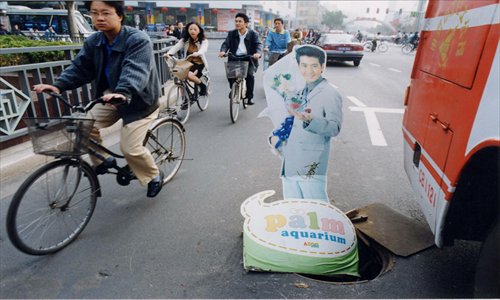 A sales sign is used to warn of the danger of an open sewer in Nanjing, Jiangsu Province. The city is spending 100,000 yuan ($16,011) on insurance to compensate people who are injured in encounters with faulty or missing sewer covers. Photo: CFP