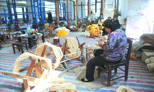 Ma Yulin, 64, a Muslim worker, spins thread in a Xingqiang Carpet factory.