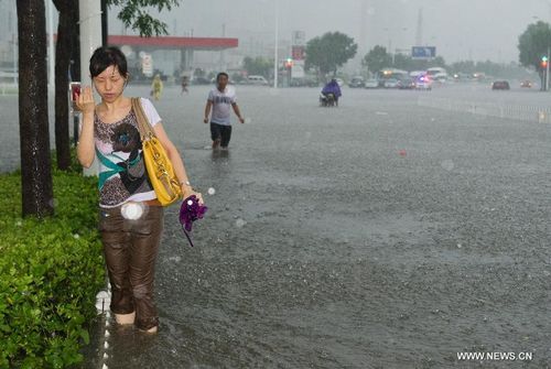 People wade through a flooded street in Tianjin, North China, July 26, 2012. Heavy rainfall hit the municipality from Wednesday afternoon to Thursday. Photo: Xinhua
