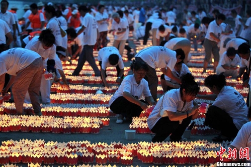 Volunteers light river lanterns. 300 people set 14630 river lanterns on the Songhua River in Ji Lin Province on July 7, 2013, creating a new Guinness World Record. (Photo: Xinhua/Chinanews.com)