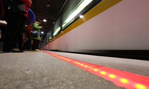 A strip of LEDs lights up the edge of the metro Line 3 platform at Yishan Road Station Monday. The LEDs replaced the yellow line that cautioned passengers not to cross before the train arrived. After a train enters the station, the multicolored LEDs change to solid blue in front of the doors to show passengers where to line up. Photo: Cai Xianmin/GT
