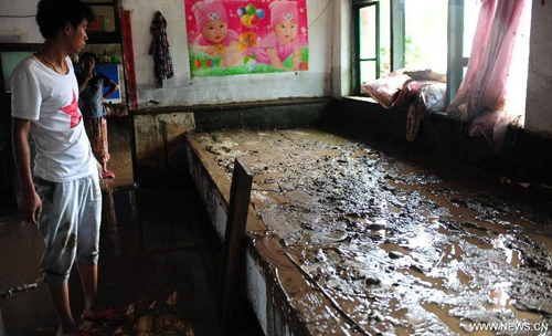 A villager looks at the mud inside his house in Daweizi village of Xiuyan County, northeast China's Liaoning Province, Aug. 5, 2012. Nearly 1.46 million people in Liaoning were affected by heavy rains and floods caused by Typhoon Damrey, authorities said Sunday. Photo: Xinhua