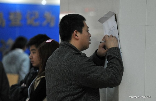 A citizen fills in a housing information form at the Housing Transaction Center in Shijiazhuang, north China's Hebei Province, March 8, 2013. Secondhand housing transaction surges in the city these days as buyers and sellers are rushing to 