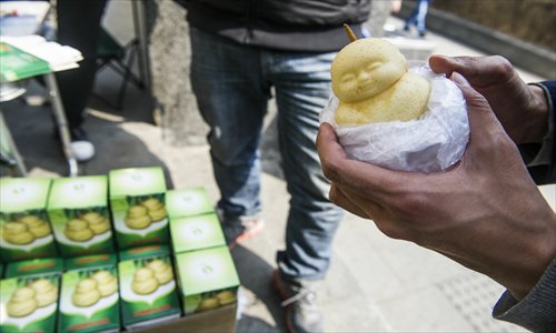 A vendor sells pears grown in the shape of a baby at the Dawanglu station, Subway Line 1 Tuesday. The pears cost 15 yuan ($2.4) each. Photo: Li Hao/GT
