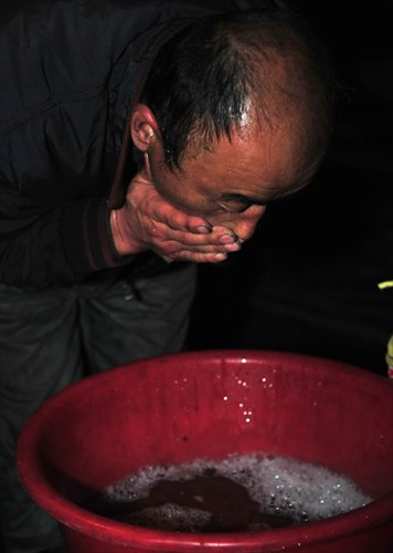 A worker washes a thick mask of coal dust off his face at the end of the day with dish-washing liquid. Photo: CFP