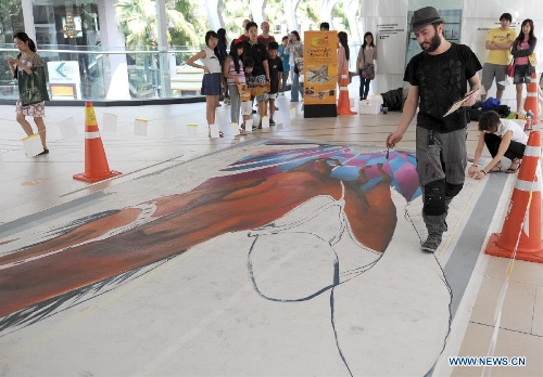 An artist draws on the ground in Bangkok, Thailand, March 2, 2013. One local artist and 19 others from over the world feast the eyes of Thai people with their 3D and 4D street paintings during the Living Arts Festival held in Bangkok.(Xinhua/Gao Jianjun) 