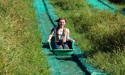 A tourist skids down the grassy hillside of Nandaihe International Entertainment Center. Photo: Courtesy of Zhang Zhichun