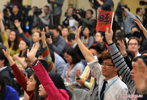 A journalist raises his notebook to attract the attention for an opportunity to asks questions at a news conference on China's currency policy and financial reform held by the first session of the 12th National People's Congress (NPC) in Beijing, capital of China, March 13, 2013. Governor Zhou Xiaochuan and other officials from China's central bank answered questions at the press conference. (Xinhua/Wang Song)