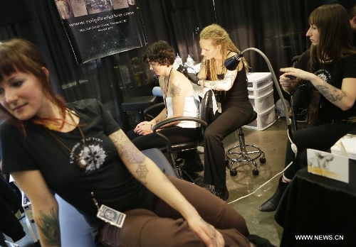 A tattoo artist works on her client's body during the 5th Vancouver tattoo and culture show in Vancouver, Canada, on April 26, 2013. The 5th Vancouver tattoo and culture show presents different tattoo art works from nearly 200 tattoo artists from across the world attracting thousands of tattoo lovers here on Friday. (Xinhua/Liang Sen) 