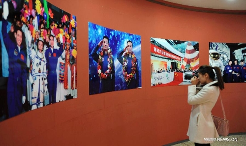 A visitor takes photo of pictures presented during the China's Space Exhibition in Hebei Museum in Shijiazhuang, capital of north China's Hebei Province, April 1, 2013. The exhibition which will last till April 7 included the display of space carriers, rocket-launcher models of the Long March series, paintings and photos related to aerospace. (Xinhua/Wang Xiao) 