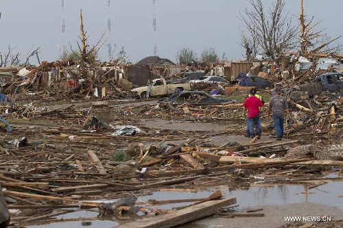 People walk through damage after a tornado in Moore, Oklahoma, the United States, on May 20, 2013. Twenty-four people were killed and 237 others injured when a massive tornado blasted the southern suburbs of Oklahoma City, the capital of the U.S. state of Oklahoma, on Monday, state officials said Tuesday. (Xinhua/Marcus DiPaola)