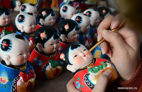 An artisan decorates the traditional Chinese clay sculptures designed with the snake image in Wuxi City, east China's Jiangsu Province, Jan. 8, 2013. The lunar year 2013 is the 