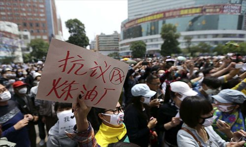A man holds a sign reading “Protest at PX Oil Refinery” during a rally in downtown Kunming, Yunnan Province against the planned construction of a CNPC petrochemical plant in the area on May 4. Photo: china.com