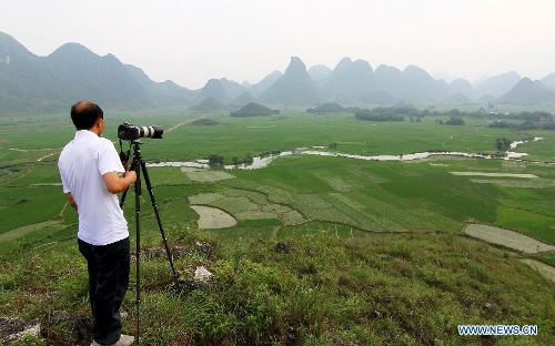 A man takes photo of the rural scenery in Guzhai Village of Liucheng County, south China's Guangxi Zhuang Autonomous Region, May 21, 2013. (Xinhua/Deng Keyi) 
