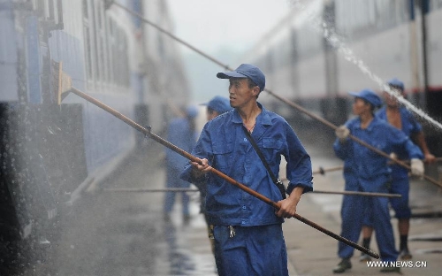 Staff members from the maintenace crew clean a train in Chengdu, capital of southwest China's Sichuan Province, July 8, 2013. Known as the