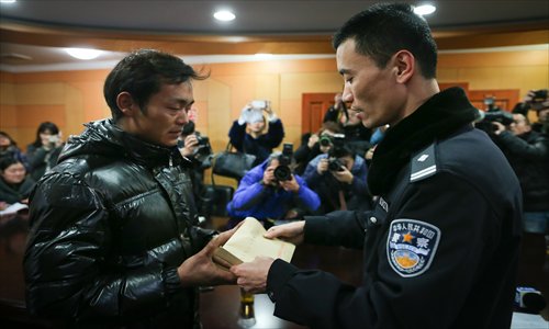 A police officer (right) hands 4,100 yuan ($657) that passersby returned to a migrant worker surnamed Qin in Xinjing Police Station in Shanghai on Monday. He was carrying a year's wages of 18,000 yuan when he fell of his motorbike Photo: Cai Xianmin/GT