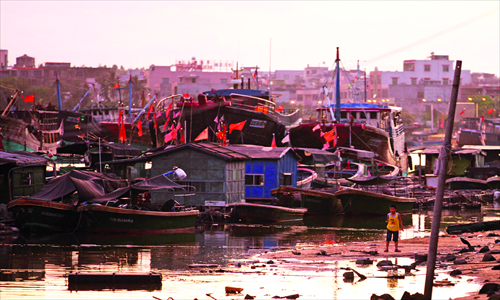 Boats and buildings at the Tanmen port take on a pink glow in the setting sun. Photo: Cai Xianmin/GT