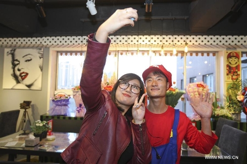 A waiter in the costume of Super Mario, a famous video game character, poses for photos with a customer at a Mario themed restaurant in Tianjin, north China, April 8, 2013. The restaurant that opened on Monday attracted many young customers due to its 