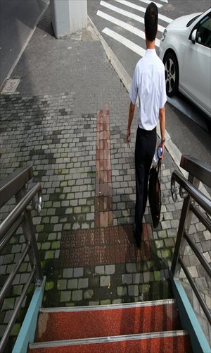 A pedestrian walks past one of the tiled paths for the blind at the crossroads of Julu Road and Chengdu Road North. Photo: Cai Xianmin/GT